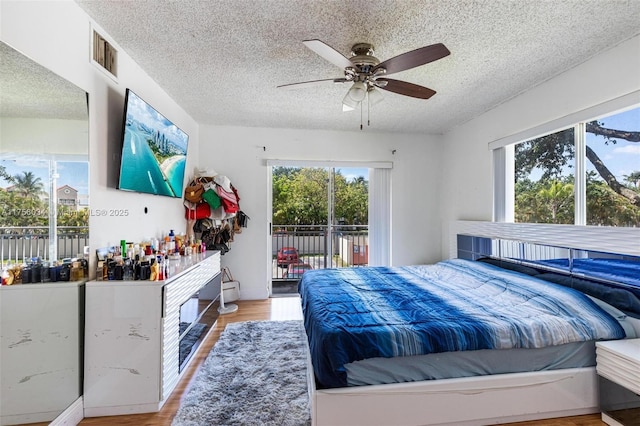 bedroom featuring access to outside, multiple windows, visible vents, and wood finished floors