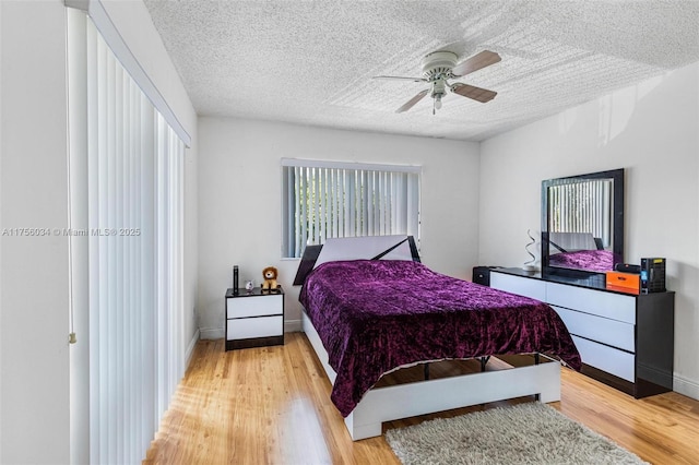 bedroom with a textured ceiling, ceiling fan, light wood-type flooring, and baseboards