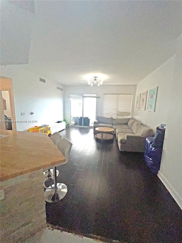 living area featuring visible vents, baseboards, and wood finished floors