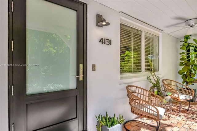 doorway to property featuring a porch and a ceiling fan