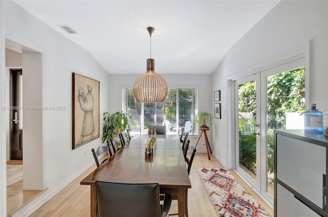 dining area with lofted ceiling, visible vents, light wood-style flooring, and baseboards