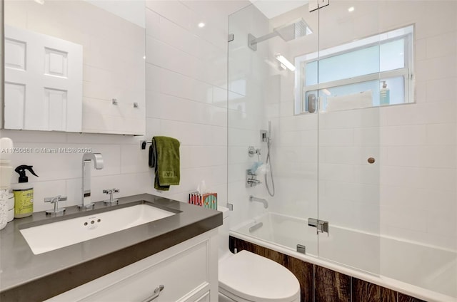 bathroom with tile walls, tasteful backsplash, toilet, enclosed tub / shower combo, and vanity