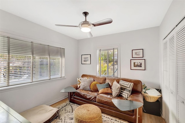 living room featuring baseboards, light wood-style flooring, and a ceiling fan