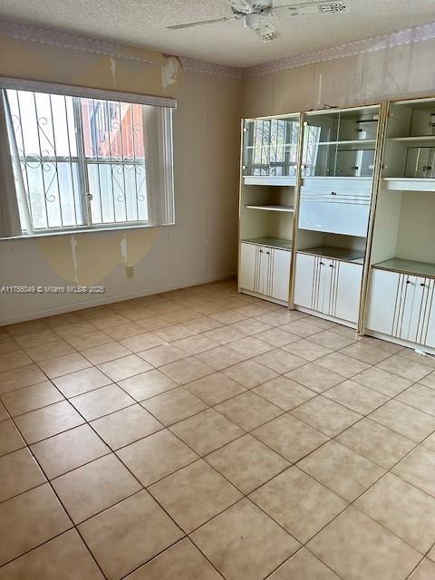 tiled spare room with ceiling fan and a textured ceiling