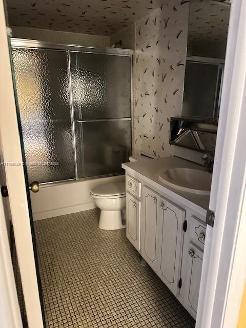 full bathroom with wallpapered walls, toilet, enclosed tub / shower combo, tile patterned floors, and vanity