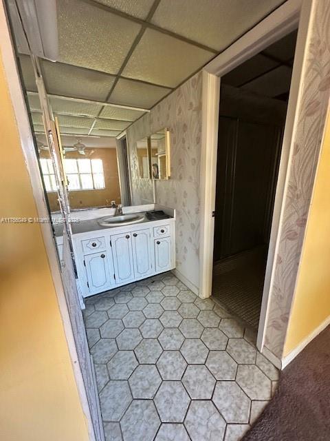 bathroom with a paneled ceiling, vanity, and baseboards