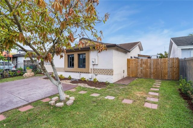 view of front of house with fence, driveway, a front lawn, and stucco siding