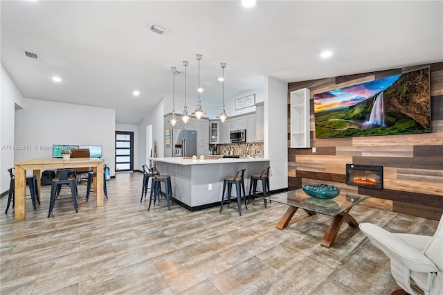 interior space with a breakfast bar area, stainless steel appliances, light countertops, visible vents, and a glass covered fireplace