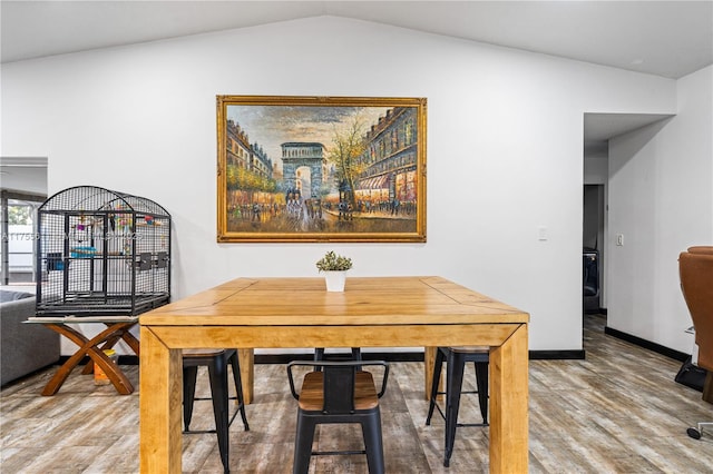 dining space with vaulted ceiling, baseboards, and wood finished floors