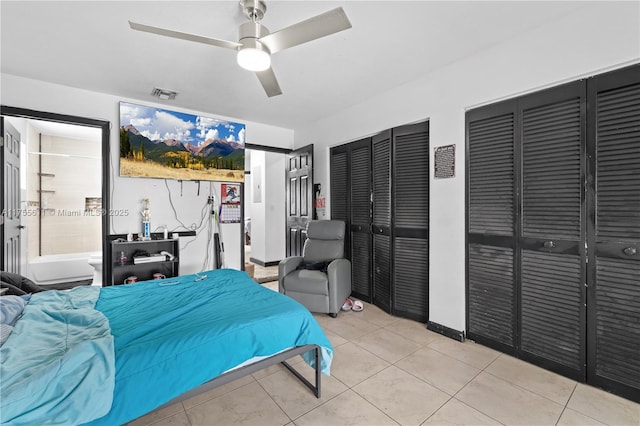 bedroom featuring light tile patterned floors, ceiling fan, visible vents, and two closets