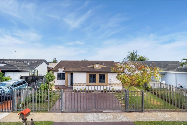 ranch-style house with a fenced front yard, a front yard, a gate, and stucco siding