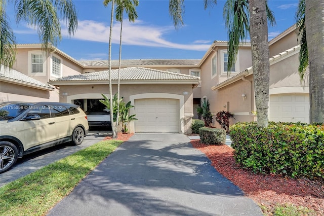 multi unit property with a tiled roof, aphalt driveway, an attached garage, and stucco siding