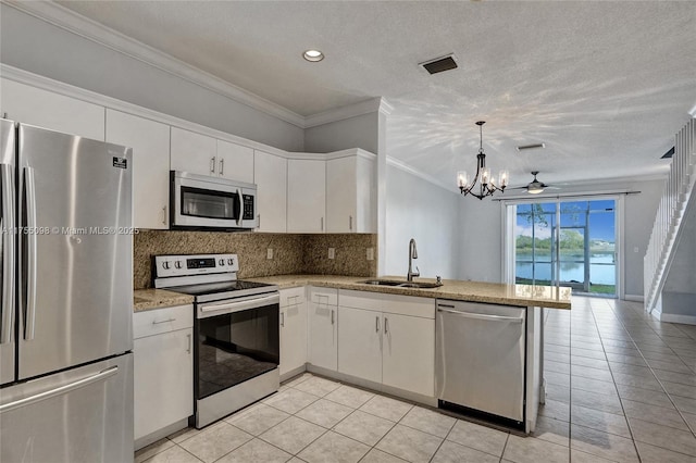 kitchen featuring ornamental molding, a peninsula, a sink, stainless steel appliances, and backsplash