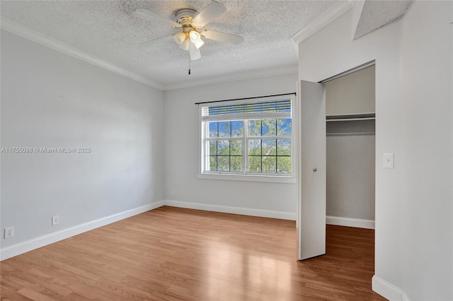 unfurnished bedroom featuring a textured ceiling, ceiling fan, wood finished floors, baseboards, and ornamental molding