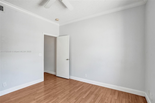 empty room featuring light wood-type flooring, baseboards, and crown molding