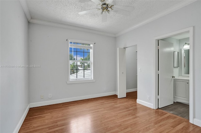 unfurnished bedroom with crown molding, light wood-style flooring, ensuite bathroom, a textured ceiling, and baseboards