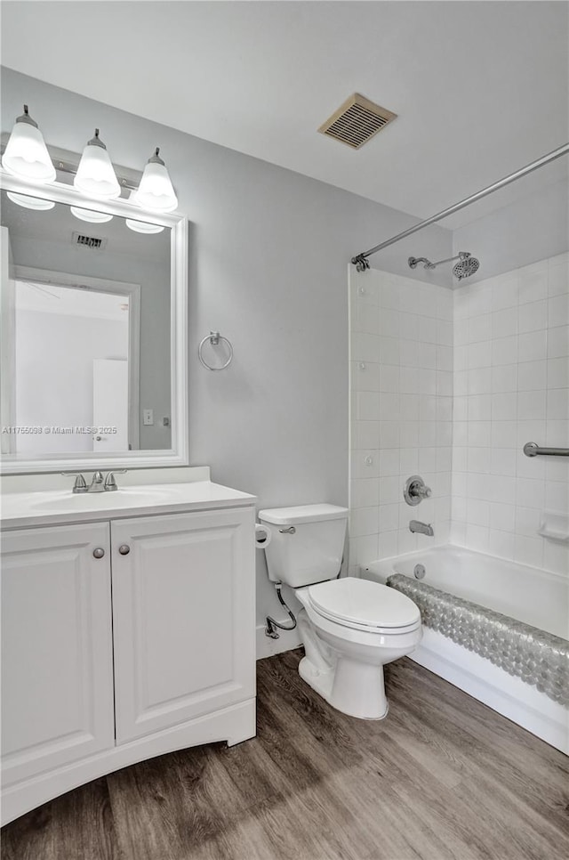 bathroom featuring toilet, shower / bath combination, wood finished floors, vanity, and visible vents