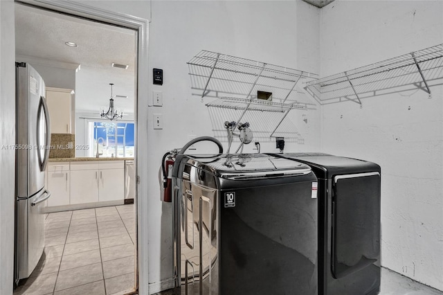 clothes washing area featuring light tile patterned floors, laundry area, washer and clothes dryer, and visible vents