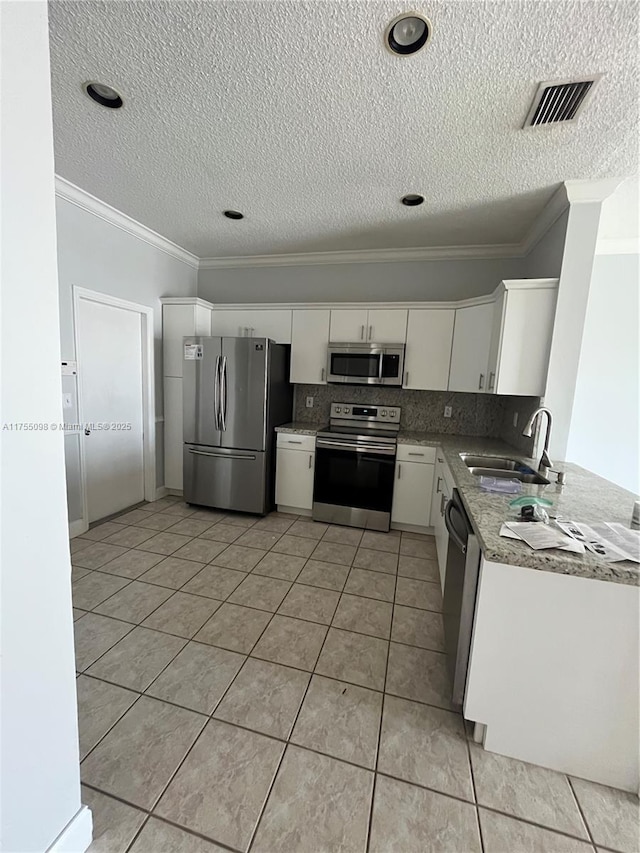 kitchen featuring visible vents, decorative backsplash, appliances with stainless steel finishes, white cabinets, and a sink