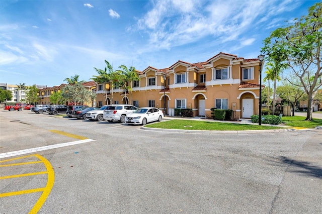 exterior space with a tile roof, uncovered parking, and stucco siding