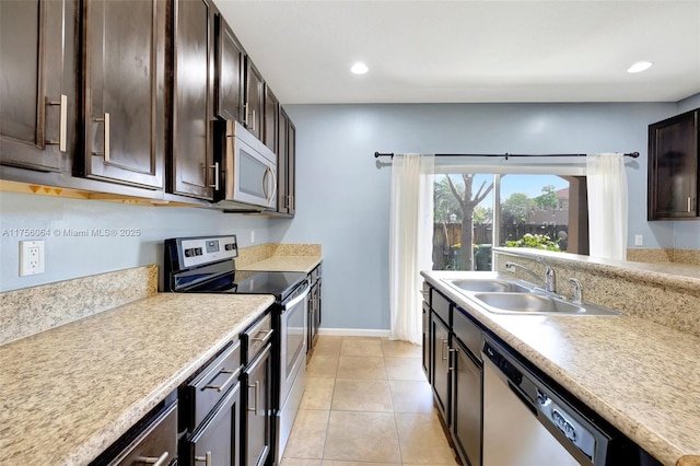 kitchen featuring light tile patterned floors, a sink, dark brown cabinets, appliances with stainless steel finishes, and light countertops