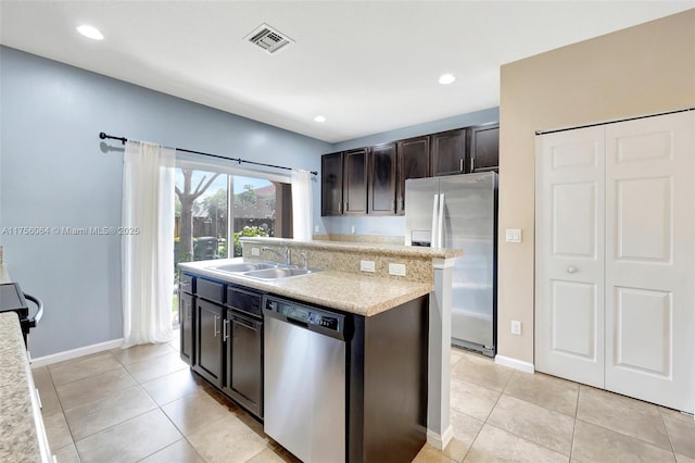 kitchen with stainless steel appliances, a sink, visible vents, light countertops, and a center island with sink