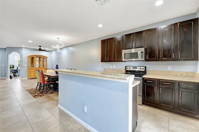 kitchen featuring arched walkways, stainless steel appliances, light tile patterned flooring, and recessed lighting