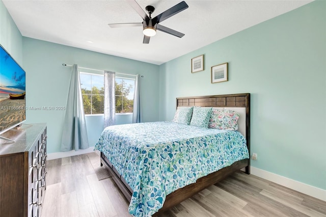 bedroom with light wood-type flooring, ceiling fan, and baseboards