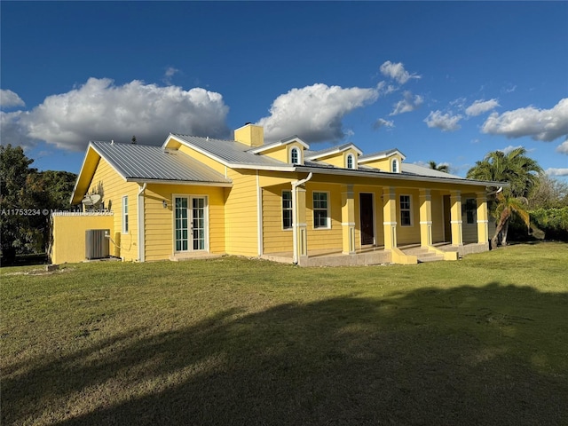 rear view of property with a chimney, a lawn, metal roof, and cooling unit