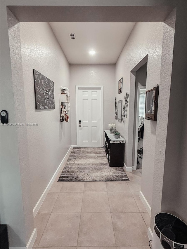 corridor with light tile patterned floors, baseboards, and visible vents