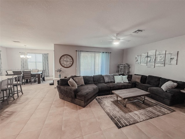 living room with a textured ceiling, ceiling fan with notable chandelier, and visible vents