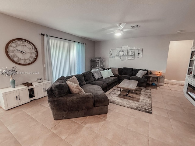 living room featuring a ceiling fan, visible vents, a textured ceiling, and light tile patterned flooring