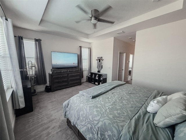 carpeted bedroom featuring ceiling fan, baseboards, visible vents, and a raised ceiling