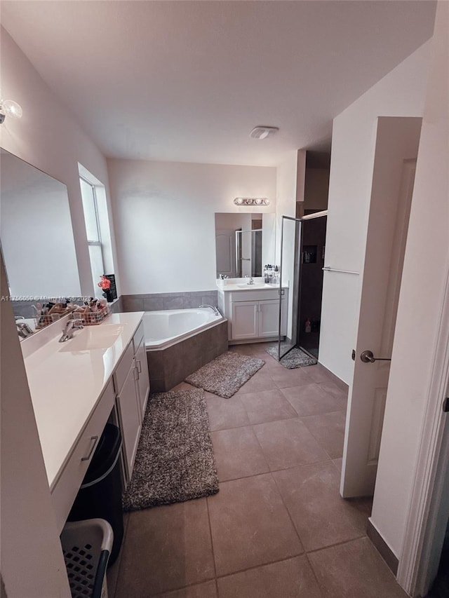 full bath with a stall shower, tile patterned floors, a sink, a garden tub, and two vanities