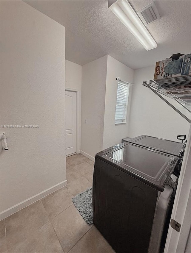 washroom with laundry area, baseboards, visible vents, washer and clothes dryer, and a textured ceiling