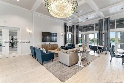 living area featuring a high ceiling, coffered ceiling, wood finished floors, and french doors