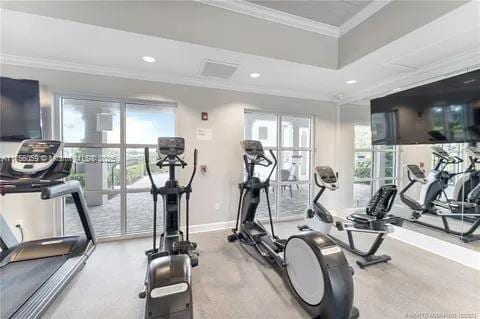 workout area with baseboards, a tray ceiling, recessed lighting, and crown molding