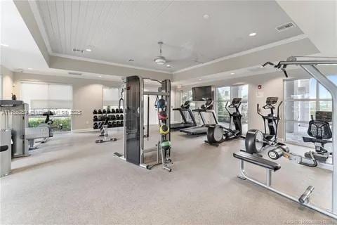 exercise room featuring a tray ceiling, ornamental molding, visible vents, and recessed lighting