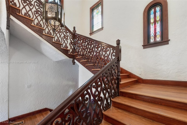 stairs with a textured wall, baseboards, and wood finished floors