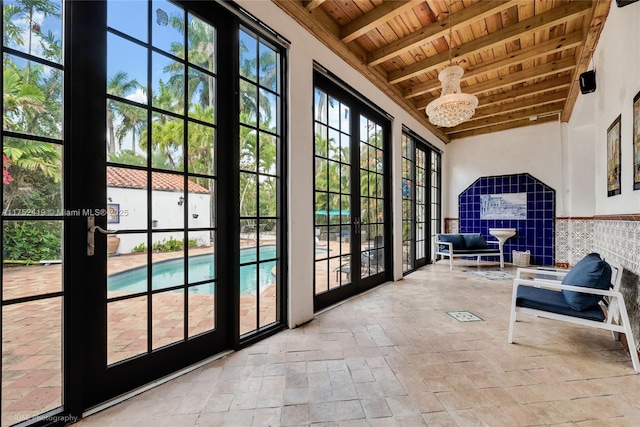 doorway to outside featuring a towering ceiling, a wealth of natural light, wood ceiling, and beamed ceiling