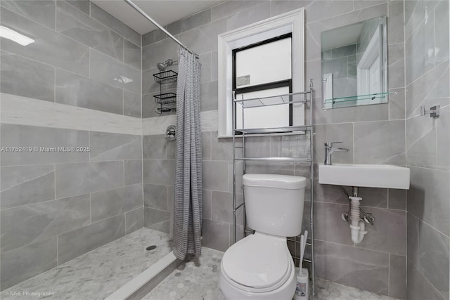 bathroom featuring tile walls, a sink, a tile shower, and toilet