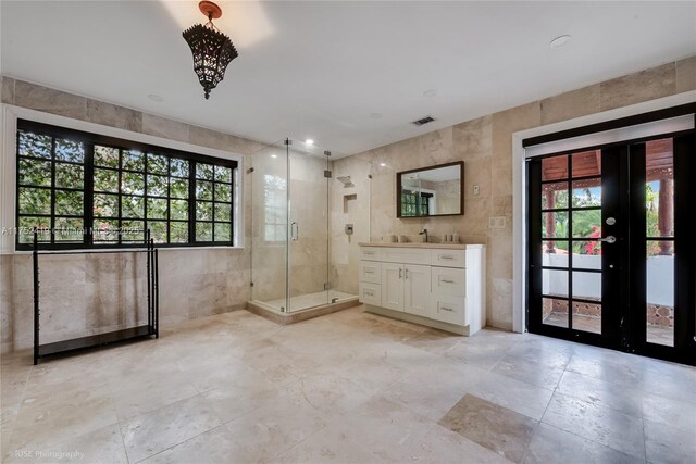 unfurnished room featuring visible vents, plenty of natural light, a sink, and tile walls