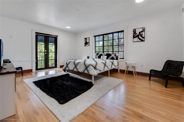 bedroom with light wood finished floors, french doors, multiple windows, and baseboards