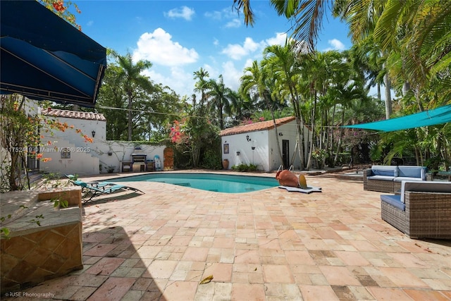 view of swimming pool with an outbuilding, a patio area, an outdoor living space, and a fenced in pool