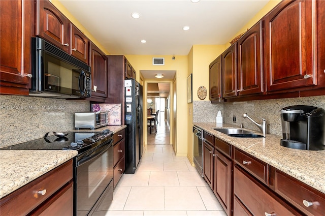 kitchen with light stone counters, reddish brown cabinets, a toaster, visible vents, and black appliances