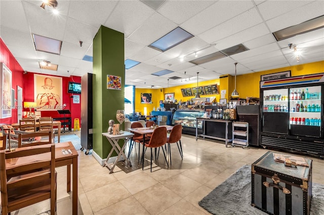 tiled dining room featuring a drop ceiling and baseboards