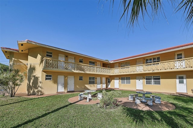 rear view of property with a patio area, a yard, and stucco siding