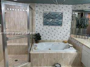 full bath with a whirlpool tub, wallpapered walls, and a stall shower