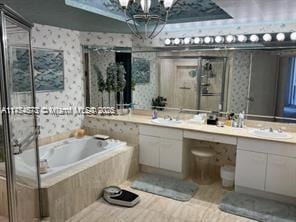 full bathroom featuring a stall shower, vanity, a bath, and wallpapered walls