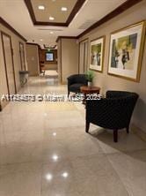 hallway with ornamental molding, a raised ceiling, and recessed lighting